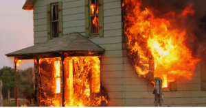 A residential house engulfed in flames, with thick black smoke billowing into the sky. Protect your home with comprehensive fire damage insurance today—get a free quote now!